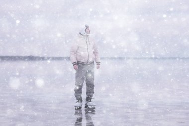 Bir adam donmuş bir gölün buzunda kayıyor, doğa manzarası, açık hava sporları.
