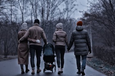 Grup arkadaşları yetişkinler kasvetli sonbaharı park eder, genç ebeveynler şehirde gezer Kasım ayında.