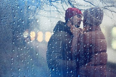 Birbirine aşık çiftler kış akşamı dışarıda sarılıyorlar, mevsimsel soyut arka plan, alacakaranlık yağmuru