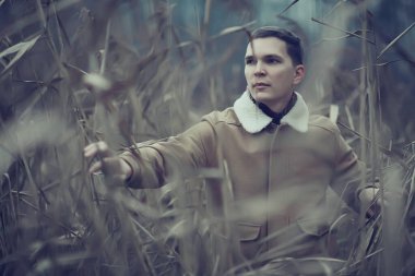 Sonbahar tarzı portrede poz veren şık genç adam, hipster doğa seyahati.