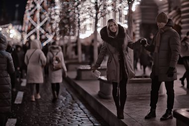 Birbirine aşık çiftler, yılbaşı yürüyüşünde şehirde akşam karları, aralık ayında yeni yıl tatili.