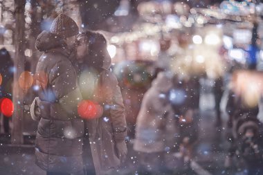 Birbirine aşık çiftler, yılbaşı yürüyüşünde şehirde akşam karları, aralık ayında yeni yıl tatili.