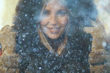 Mutlu kız akşam alışverişi yapıyor. Dükkanın penceresinin yanında duruyor.