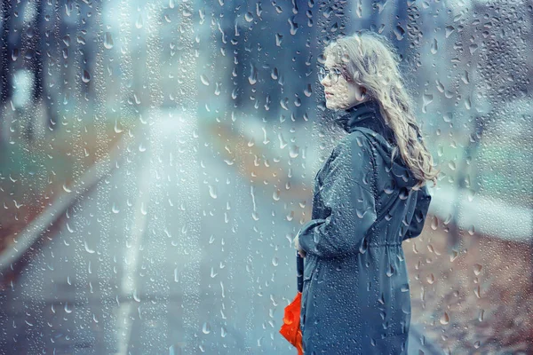 seasonal autumn pornetret, sad girl behind wet glass, raindrops background