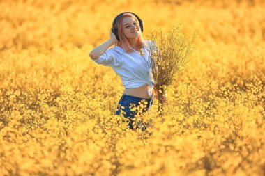 Sesli kulaklıklar. Yaz kız müziği. Çiçek tarlasında, genç dişi baharda.