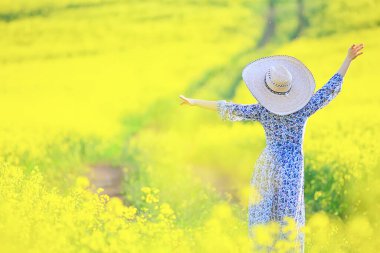 Çekici, aktif, güzel bir kadın, özgürce arkadan mutlu bir manzara, bir çiçek tarlasında.