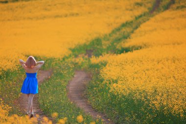Çekici, aktif, güzel bir kadın, özgürce arkadan mutlu bir manzara, bir çiçek tarlasında.