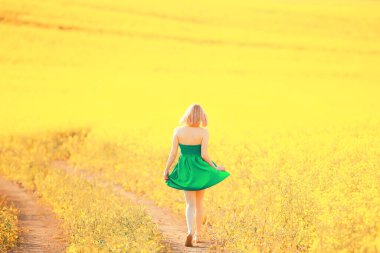 Bahar doğası. Çiçek tarlasında genç bir kız. Güneşli bir manzarada bir bayanın özgürlüğü ve mutluluğu.