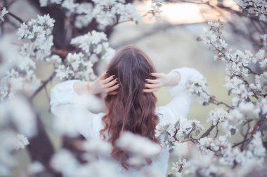 Kız arkasını görür, bahar portresi mutlu kız çiçek açan bahçede, mevsimlik nisan ayında