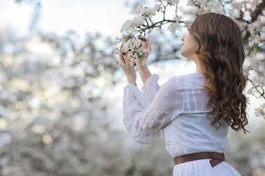 Kız arkasını görür, bahar portresi mutlu kız çiçek açan bahçede, mevsimlik nisan ayında