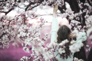Kız arkasını görür, bahar portresi mutlu kız çiçek açan bahçede, mevsimlik nisan ayında