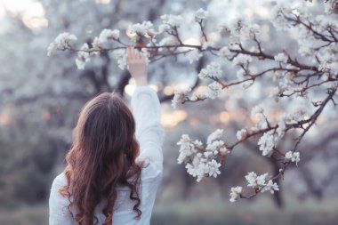 Kız arkasını görür, bahar portresi mutlu kız çiçek açan bahçede, mevsimlik nisan ayında