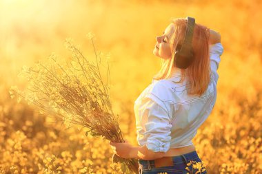 Kulaklıklı bir kızın çiçek tarlasında müzik dinlemesi, bahar müziği mutludur.