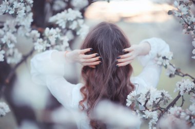 Kız arkasını görür, bahar portresi mutlu kız çiçek açan bahçede, mevsimlik nisan ayında