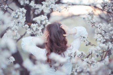 Kız arkasını görür, bahar portresi mutlu kız çiçek açan bahçede, mevsimlik nisan ayında