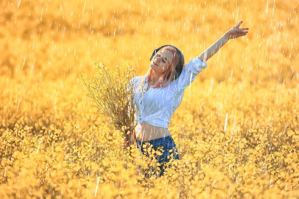 girl with headphones listening to music in summer rain outside summertime music