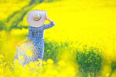 Çekici, aktif, güzel bir kadın, özgürce arkadan mutlu bir manzara, bir çiçek tarlasında.