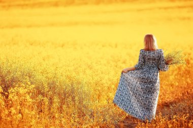 Çekici, aktif, güzel bir kadın, özgürce arkadan mutlu bir manzara, bir çiçek tarlasında.