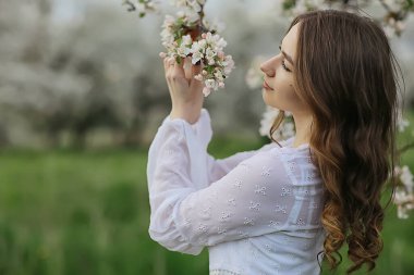 Kız arkasını görür, bahar portresi mutlu kız çiçek açan bahçede, mevsimlik nisan ayında