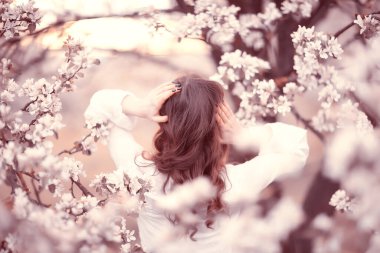 Kız arkasını görür, bahar portresi mutlu kız çiçek açan bahçede, mevsimlik nisan ayında