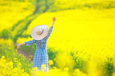 Çekici, aktif, güzel bir kadın, özgürce arkadan mutlu bir manzara, bir çiçek tarlasında.