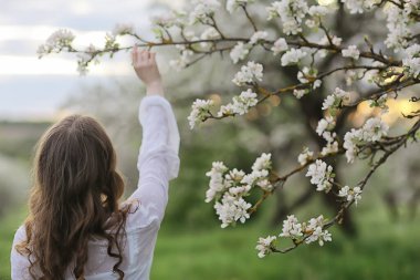 Kız arkasını görür, bahar portresi mutlu kız çiçek açan bahçede, mevsimlik nisan ayında