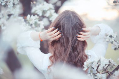 Kız arkasını görür, bahar portresi mutlu kız çiçek açan bahçede, mevsimlik nisan ayında