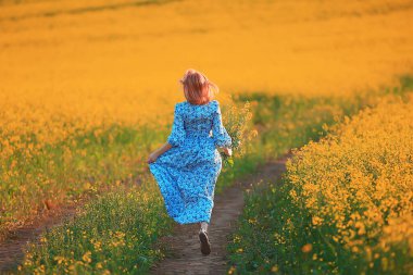 Çekici, aktif, güzel bir kadın, özgürce arkadan mutlu bir manzara, bir çiçek tarlasında.