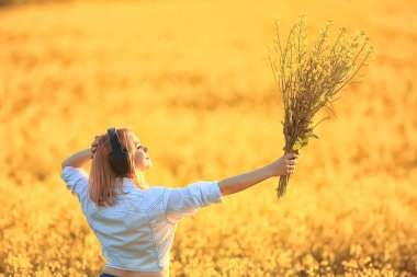Sesli kulaklıklar. Yaz kız müziği. Çiçek tarlasında, genç dişi baharda.