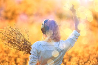 Kulaklıklı bir kızın çiçek tarlasında müzik dinlemesi, bahar müziği mutludur.