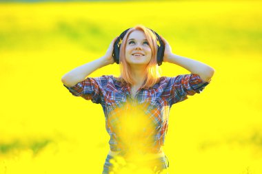 Sesli kulaklıklar. Yaz kız müziği. Çiçek tarlasında, genç dişi baharda.