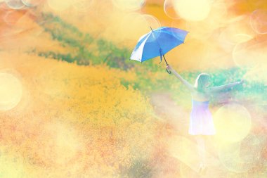 Çiçeklerle dolu bir yaz tarlasında şemsiyesi olan bir kız. Kadın doğası sarı tarla.