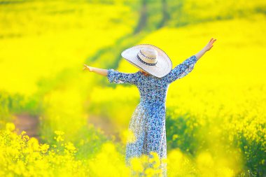 Çekici, aktif, güzel bir kadın, özgürce arkadan mutlu bir manzara, bir çiçek tarlasında.