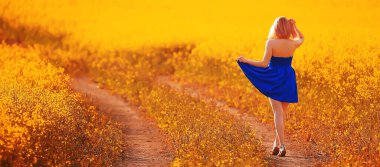 Çekici, aktif, güzel bir kadın, özgürce arkadan mutlu bir manzara, bir çiçek tarlasında.