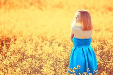 Çekici, aktif, güzel bir kadın, özgürce arkadan mutlu bir manzara, bir çiçek tarlasında.