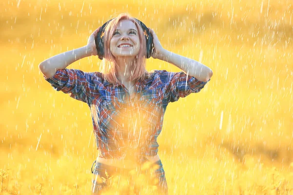 girl with headphones listening to music in summer rain outside summertime music