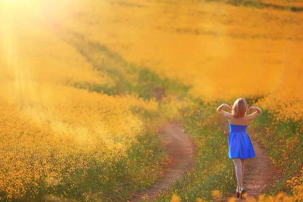 Çekici, aktif, güzel bir kadın, özgürce arkadan mutlu bir manzara, bir çiçek tarlasında.