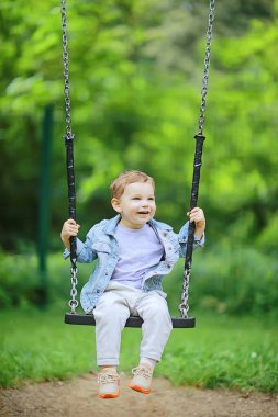 Bahar geldi, baharda bir çocuk sallanıyor salıncakta, keyifli bir çocukluk dönemi mutlu bir yaz çocuğu.