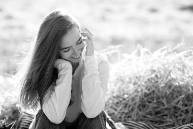 Siyah beyaz, neşeli bir kızın taşra tarzı portresi, saman tarlasında özgürlüğüne kavuşmuş genç bir kadın.