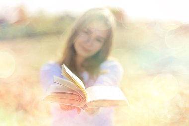 Yazın tarlada kitap okuyan bir kadın bir kitap okuyor. Bir kitap okuyor. Okul kızından yaz tatilini tarlada okuyor.