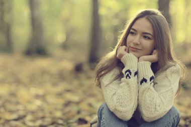 Sonbahar parkında oturan kız, sonbahar mevsimi Eylül ayında ormanda.