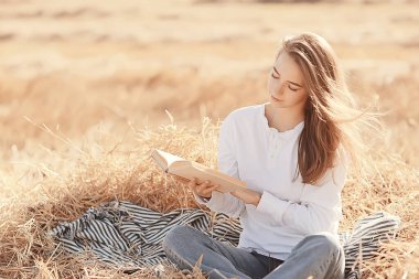 Yazın tarlada kitap okuyan bir kadın bir kitap okuyor. Bir kitap okuyor. Okul kızından yaz tatilini tarlada okuyor.