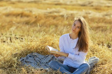 Yazın tarlada kitap okuyan bir kadın bir kitap okuyor. Bir kitap okuyor. Okul kızından yaz tatilini tarlada okuyor.
