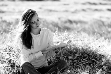 Yazın tarlada kitap okuyan bir kadın bir kitap okuyor. Bir kitap okuyor. Okul kızından yaz tatilini tarlada okuyor.