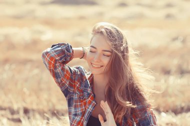 Mutlu neşeli kız yazın gülümsüyor. Tarla resminde, genç kız mutluluk dolu bir hayat sürüyor.