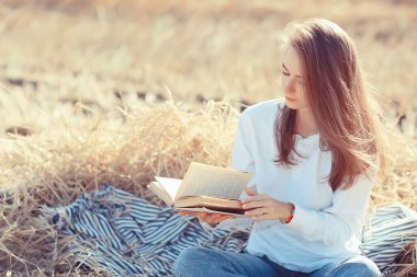 Yazın tarlada kitap okuyan bir kadın bir kitap okuyor. Bir kitap okuyor. Okul kızından yaz tatilini tarlada okuyor.
