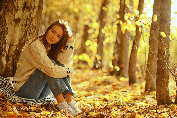 Girl sitting autumn park, autumn season september in the forest