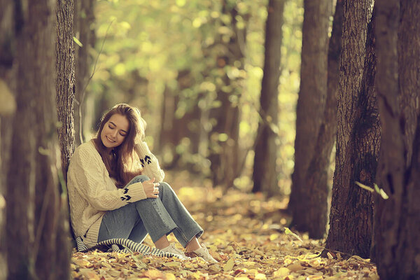 Girl sitting autumn park, autumn season september in the forest