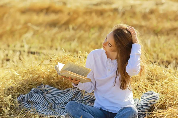 女がフィールドで本を読む夏のわら女がフィールドの女子学生から夏休みを勉強する本を読む — ストック写真