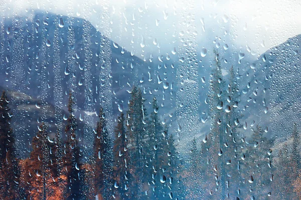 rain window view, water drops on glass view forest and mountains landscape background